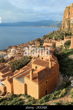 Vue sur le château médiéval fortifié Monemvasia avec mer Égée et côte comme arrière-plan. Maisons en pierre avec toits de terre cuite rose poussiéreux et mer bleue Banque D'Images