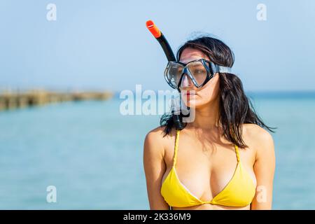 femme en bikini jaune et de la plongée ramasser une poubelle en plastique de la mer Banque D'Images