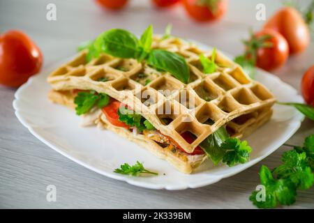 Sandwich de deux omelettes aux œufs avec bacon et tomates à l'intérieur, en forme de gaufre. Banque D'Images