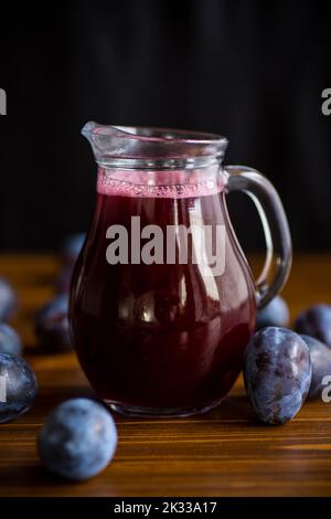 sirop de prune sucré dans un verre de décanter sur une table en bois Banque D'Images