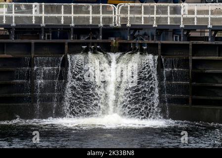 Début du canal calédonien, près de fort William, l'eau coule de la porte d'écluse, avec bateau à passagers attendant derrière, soirée d'été comme coucher de soleil, réflecti Banque D'Images