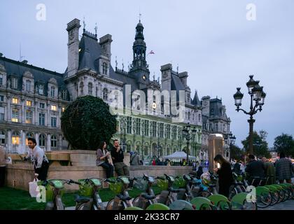 Les Vélib verts sont soigneusement garés par l'Hôtel de ville de Paris où un spectacle lumineux est projeté sur sa façade Banque D'Images