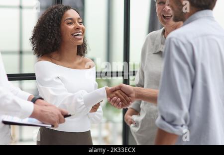 Des hommes d'affaires multiethniques souriants se mêlant au bureau Banque D'Images