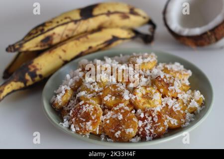 Tranches de plantain mûres rôties au ghee, enrobées de mélange de sucre de coco. Un en-cas spécial du Kerala. Prise de vue sur fond blanc Banque D'Images