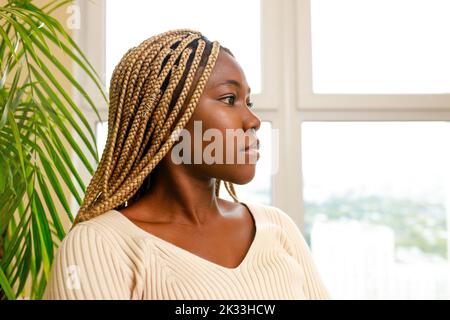 femme brésilienne avec des dreadlocks jaunes assis dans le salon Banque D'Images