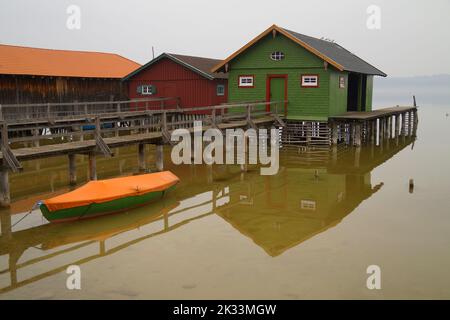 Long quai en bois menant aux maisons de bateau colorées sur le lac Ammersee dans le village bavarois de Schondorf le jour sombre et brumeux (Bavière, Allemagne) Banque D'Images