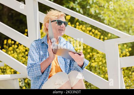 Femme authentique senior utilisant un ordinateur portable pour l'enseignement à distance en plein air Banque D'Images