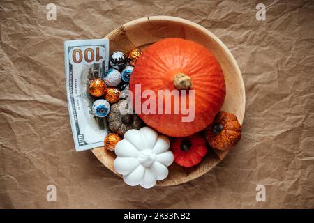 Économisez de l'argent Halloween, économisez, Halloween sur le budget. Billets de banque en espèces sur le fond de décoration de citrouille d'Halloween Banque D'Images