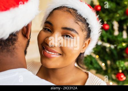 couple hispanique latin s'embrassant les uns les autres près de l'arbre de noël à la maison Banque D'Images