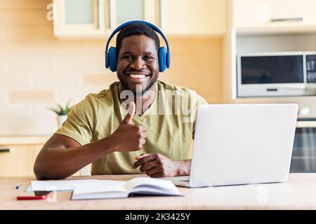 homme hispanique qui écoute de la musique dans un casque sans fil et travaille avec un ordinateur portable à la maison Banque D'Images