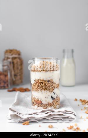 Pain de granola et de yaourt dans un verre en forme de pot, avoine et noix de parapain, pain de miel grillé avec des couches de yaourt dans une tasse en verre de pot Banque D'Images