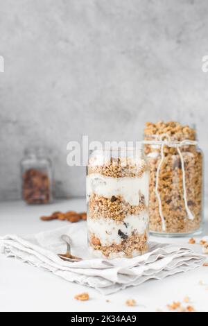 Pain de granola et de yaourt dans un verre en forme de pot, avoine et noix de parapain, pain de miel grillé avec des couches de yaourt dans une tasse en verre de pot Banque D'Images