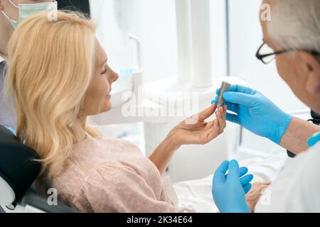 Médecin sélectionnant la prothèse pour les dents du patient Banque D'Images