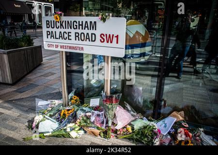 Hommages floraux à la Reine entourent un panneau de chemin dans Buckingham Palace Road Banque D'Images