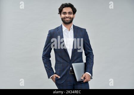 Jeune homme d'affaires arabe indien souriant portant un costume isolé sur beige, portrait. Banque D'Images
