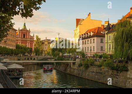 Ljubljana,Slovénie-sept 3rd 2022.Un bateau touristique passe le long de la rivière Ljubljana à Ljubljana. Passerelle Fishmarket, Triple Bridge en arrière-plan Banque D'Images