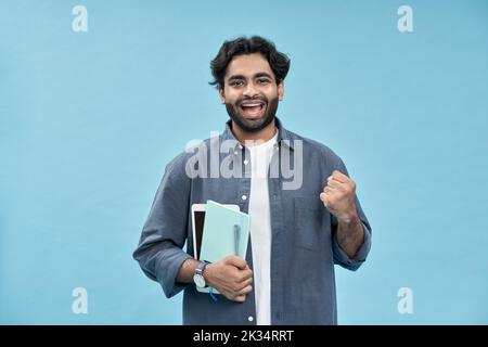 Heureux arabe jeune homme étudiant gagnant isolé sur bleu célébrant la bourse. Banque D'Images