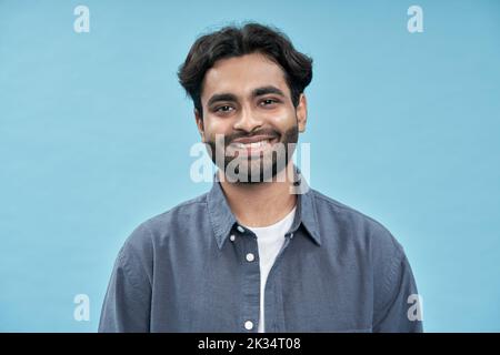 Souriant et confiant, jeune arabe se tenant isolé sur fond bleu. Banque D'Images