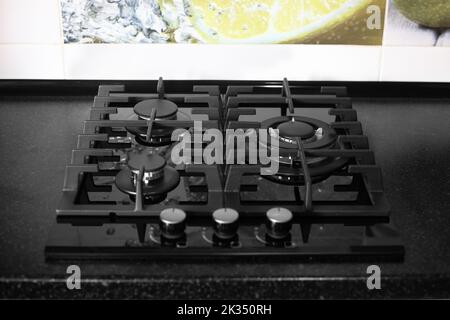 Un poêle à gaz à trois brûleurs avec un dessus en verre trempé est construit dans un comptoir noir dans la cuisine. Foyer sélectif. Banque D'Images