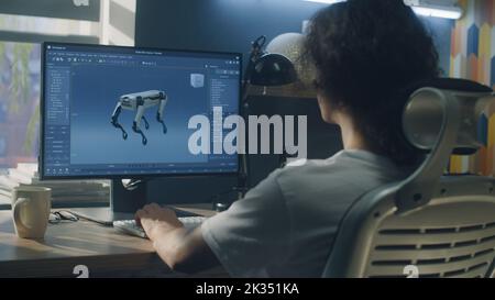 Homme assis à la table et créant 3D prototype de robot moderne tout en travaillant sur pc dans 3D programme de modélisation à distance du bureau à domicile Banque D'Images