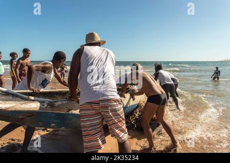 Les pêcheurs poussant un canot dans la mer pour la livraison de cadeaux Iemanja à la plage de Boca do Rio Banque D'Images