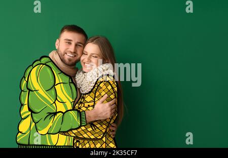 Joyeux jeune couple en manteaux dessinés sur fond vert Banque D'Images