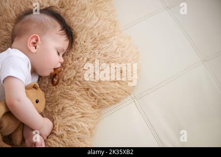 Il a toujours nap après avoir allaiter. Un adorable bébé garçon prenant une sieste. Banque D'Images