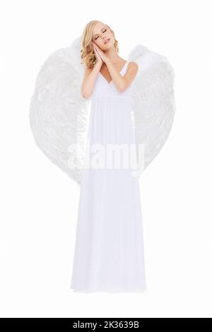 Un innocent sucré. Photo studio d'une jeune femme dans des ailes d'ange isolées sur blanc. Banque D'Images