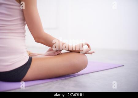 Trouver la paix intérieure. Une jeune femme méditant dans un studio de yoga. Banque D'Images