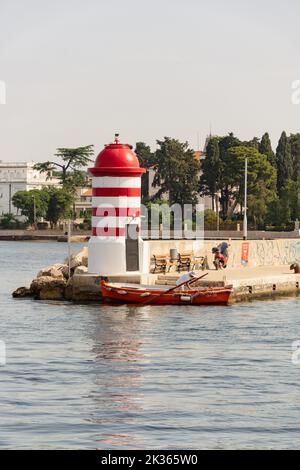 Une photo verticale d'un phare et d'un bateau de pêche sur la côte à Zadar, en Croatie Banque D'Images