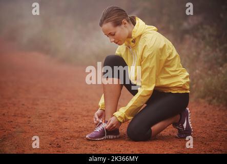 Laçage avant sa course. Une jeune coureuse noue ses lacets pendant son entraînement. Banque D'Images