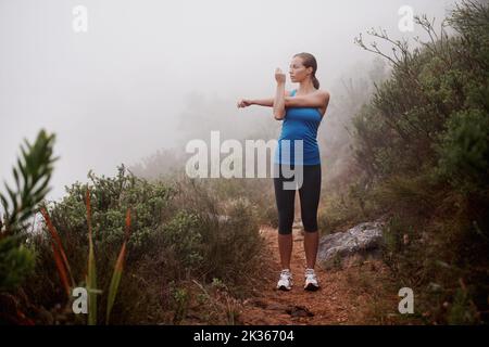 Libérer ses muscles avant qu'elle ne les travaille. Une jeune femme qui s'entraîne à l'extérieur. Banque D'Images
