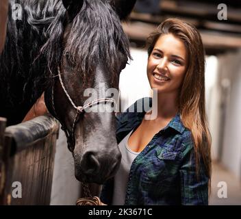 Juste moi et mon cheval. Une jeune femme dans une écurie avec son cheval. Banque D'Images