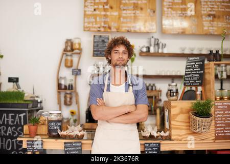 Toujours un visage sympa au café. Portrait d'un barista masculin se tenant au comptoir d'un café. Banque D'Images
