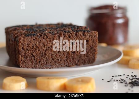 Gâteau Ragi plantain. Gâteau au thé sans gluten composé de farine de millet et de plantain mûr en purée, parsemé de graines de sésame noir. Prise de vue en blanc Banque D'Images