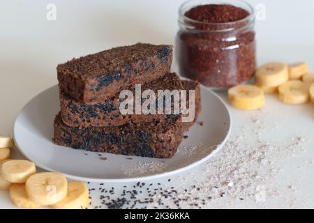 Gâteau Ragi plantain. Gâteau au thé sans gluten composé de farine de millet et de plantain mûr en purée, parsemé de graines de sésame noir. Prise de vue en blanc Banque D'Images