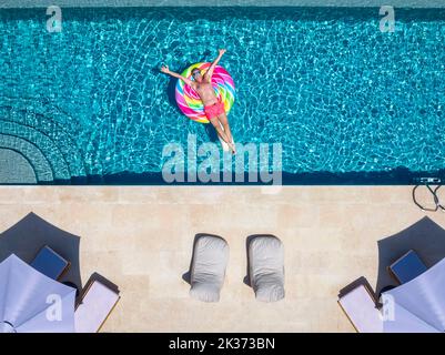 Vue aérienne d'un heureux homme flottant sur un jouet gonflable dans une piscine Banque D'Images