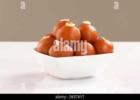 Gulab Jamun avec amande et safran servi dans un bol blanc. Indian Sweet Gulab jamun vue rapprochée. Isolé sur fond blanc Banque D'Images