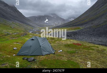 Tente extérieure verte dressée dans une vallée arctique dure et éloignée, le jour de l'été, nuageux et pluvieux. Col Basstavagge dans le parc national de Sarek, Laponie, Suède Banque D'Images