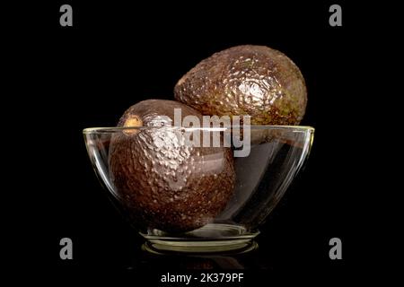 Deux avocats mûrs dans un bol en verre, macro, isolé sur fond noir. Banque D'Images