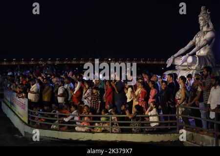 Rishikesh, Uttarakhand, Inde. 23rd septembre 2022. Les dévotés se tiennent devant la statue de Shiva construite sur un pont au-dessus du Gange et regardent la soirée quotidienne Aarti interprétée par le chef spirituel et les disciples de Parmarth Niketan Ashram. Parmarth Niketan fondé en 1942 par Pujya Swami Sukhdevanandji Maharaj est le plus grand Ashram de Rishikesh, avec plus de 1000 chambres fournissant une atmosphère propre, pure et sacrée avec des jardins abondants et magnifiques à des milliers de pèlerins qui viennent de tous les coins de la Terre. Les activités quotidiennes du Parmarth Niketan incluent le yoga quotidien spécialisé dans le Vinyasa Yoga, Banque D'Images