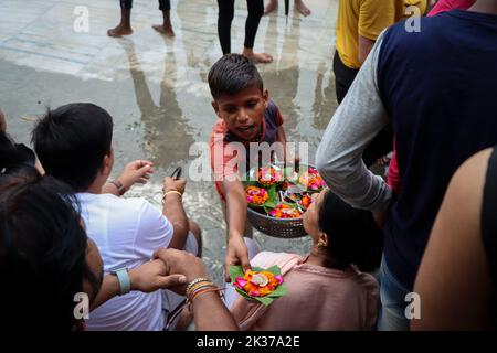 Rishikesh, Uttarakhand, Inde. 23rd septembre 2022. Un jeune garçon vend des fleurs pour Ganga Aarti aux dévotés participant au rituel quotidien du soir. Parmarth Niketan fondé en 1942 par Pujya Swami Sukhdevanandji Maharaj est le plus grand Ashram de Rishikesh, avec plus de 1000 chambres fournissant une atmosphère propre, pure et sacrée avec des jardins abondants et magnifiques à des milliers de pèlerins qui viennent de tous les coins de la Terre. Les activités quotidiennes du Parmarth Niketan comprennent le yoga quotidien spécialisé dans le Vinyasa Yoga, le yoga général Hatha, et le yoga Nindra, les prières universelles du matin et les cours de méditation, les sats quotidiens Banque D'Images