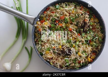 Viande de riz légumes dans une casserole. Riz basmati cuit avec légumes sautés et mouton rôti garni d'oignons de printemps. Prise de vue sur fond blanc Banque D'Images