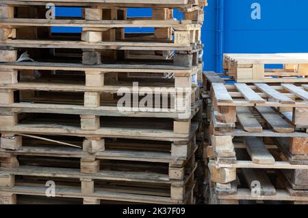 Une pile de palettes en bois contre le mur bleu Banque D'Images