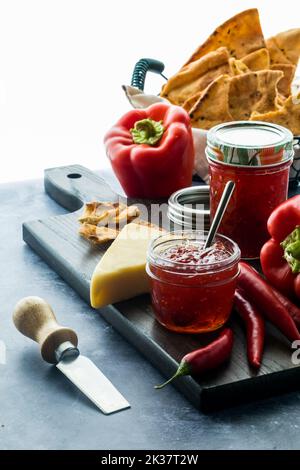 Un arrangement de gelée de piment avec du fromage et des crackers, éclairé par derrière. Banque D'Images