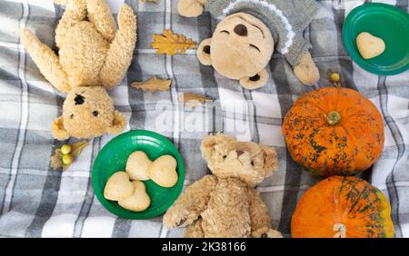 Pique-nique d'automne. Ours en peluche couchés sur une couverture à carreaux. Citrouilles, feuilles d'automne, biscuits en forme de cœur. Banque D'Images