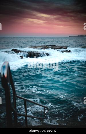 Piscine à côté de l'océan dans les tons chauds du lever du soleil à Sydney, Nouvelle-Galles du Sud, Australie Banque D'Images