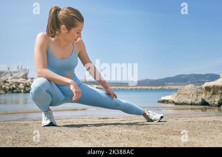 Sportswoman effectuant une fente latérale sur un remblai contre la mer