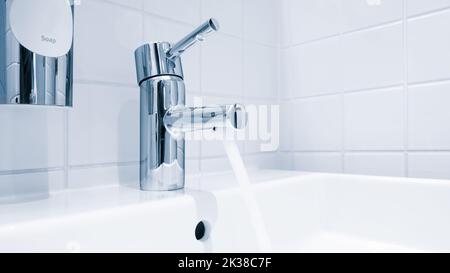 Mélangeur d'eau dans la salle de bains. Robinet d'eau en chrome, robinet avec eau en bleu Banque D'Images