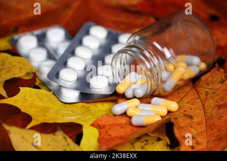 Pilules sur les feuilles d'érable d'automne, bouteille avec capsules dispersées. Pharmacie, antidépresseurs, vitamines pour l'immunité en saison de la grippe Banque D'Images